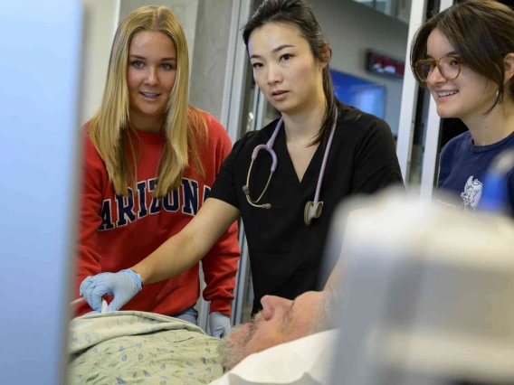 Female medical instructor working with students and patient in clinical setting.